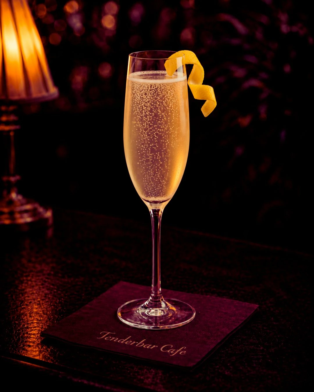 French 75 koktel u flute čaši sa šampanjcem, džinom i limunom, lagano penušav i ukrašen twistom limuna.