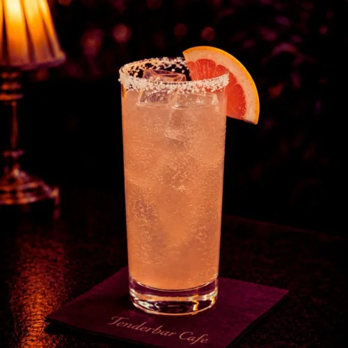 Paloma koktel u highball čaši sa ledom, tekila blanko, sok od limete i grejpfruta, soda, salt rim i kriška grejpfruta.